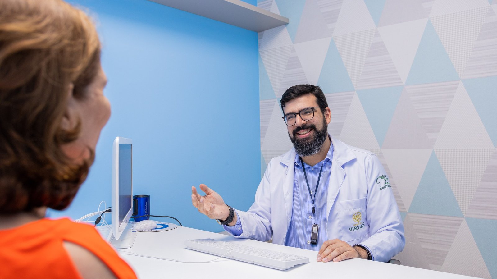 Profissional de saúde conversa com paciente em ambiente de atendimento.